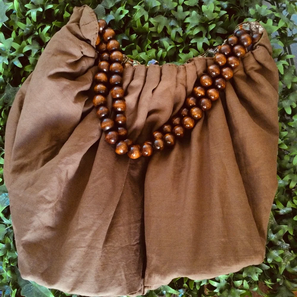Reversible hobo tote with brown wood balls straps. Has a tie strap closu…